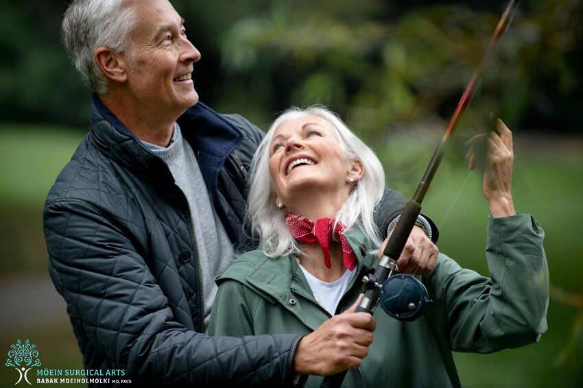 An older couple holding a fishing rod.