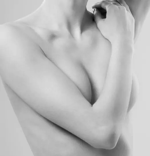 A black and white image captures a person with crossed arms over their chest, shown from shoulders to waist, exuding an air of quiet confidence—perfectly embodying the essence of a remote consultation professional.
