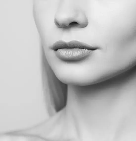 Black and white close-up of the lower half of a woman's face, subtly capturing her lips and part of her nose against a plain background, evokes an aura perfect for promoting digital consultation services.