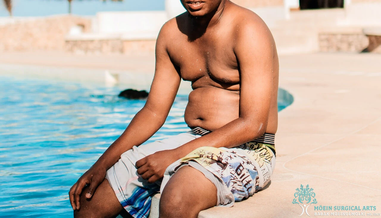 A man sitting on the edge of a swimming pool.