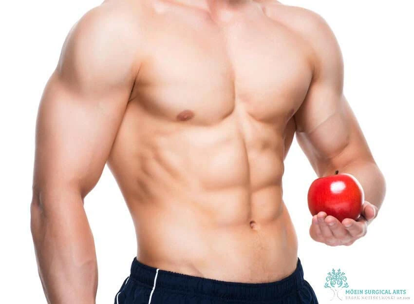 A man without a shirt holding an apple.