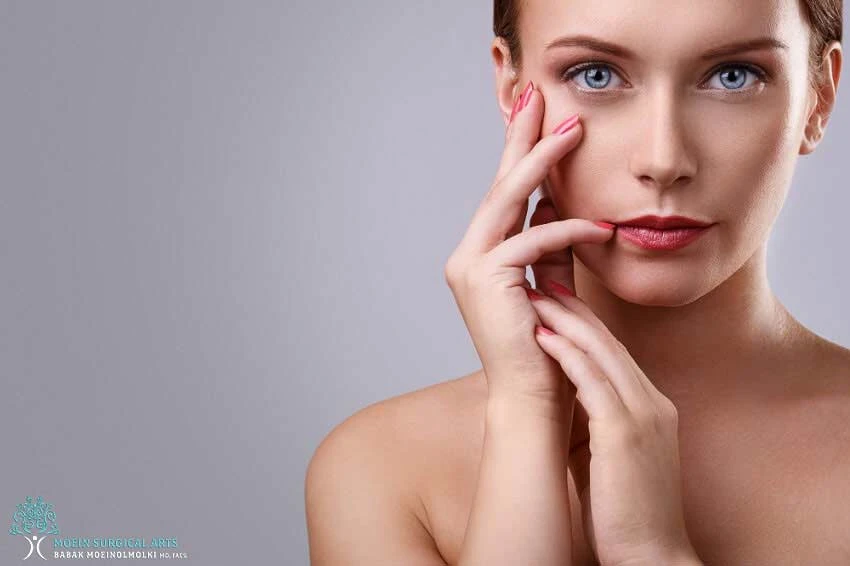 A woman posing with her hands on her face.