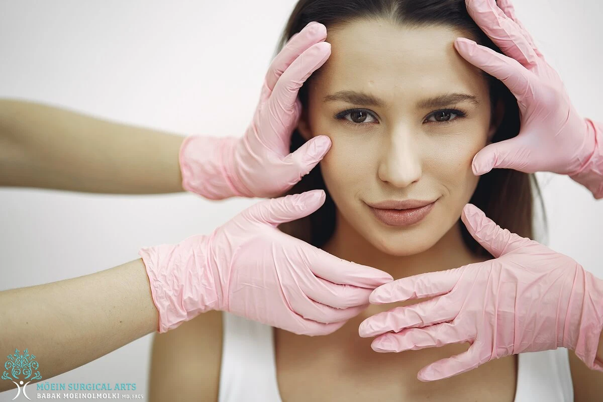 A woman with pink gloves on her face.