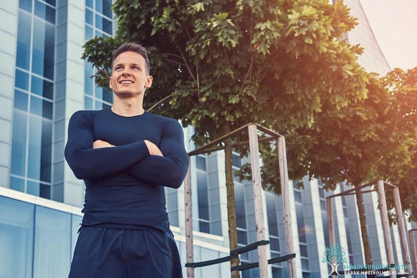 A man standing in front of a building with his arms crossed.