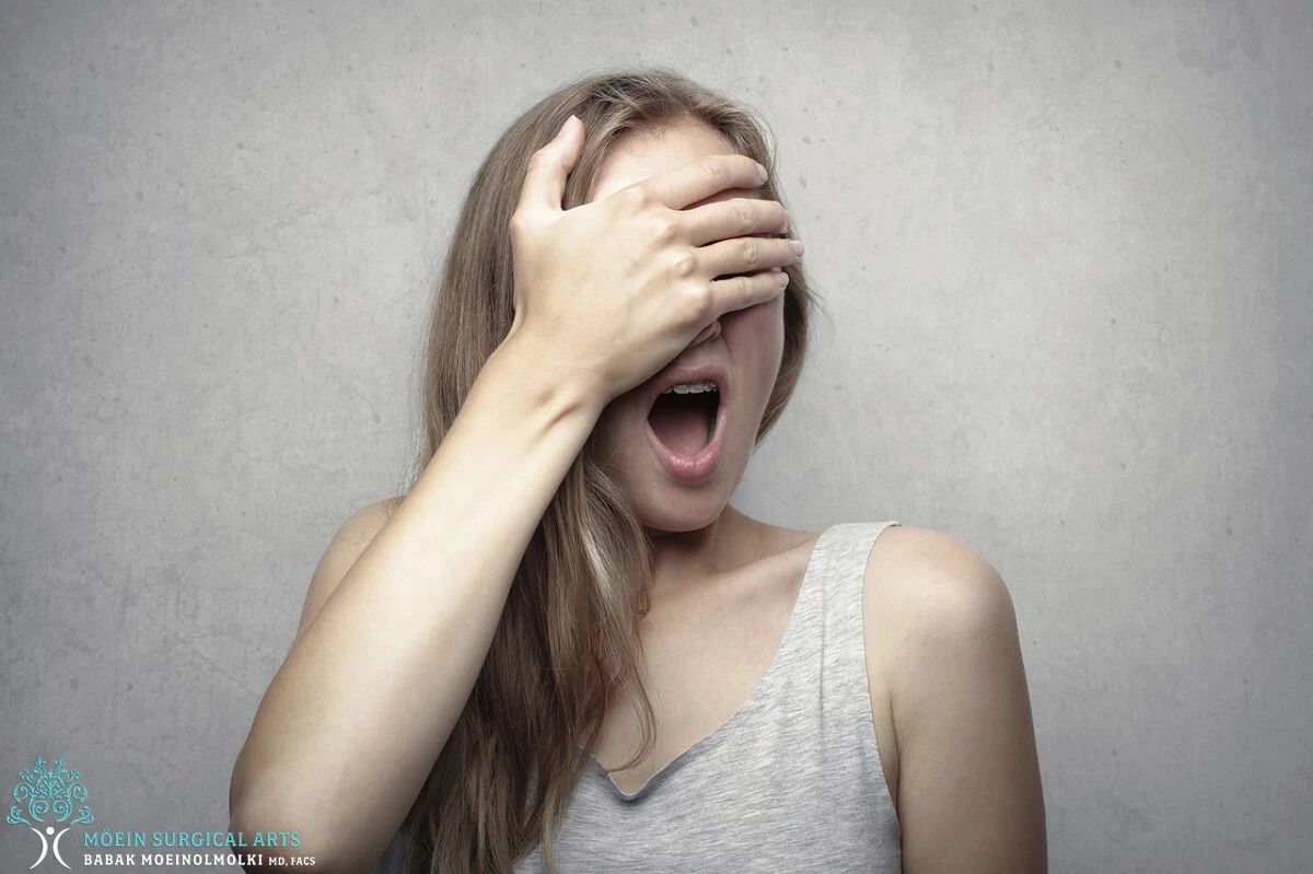 A woman covering her eyes with her hands.