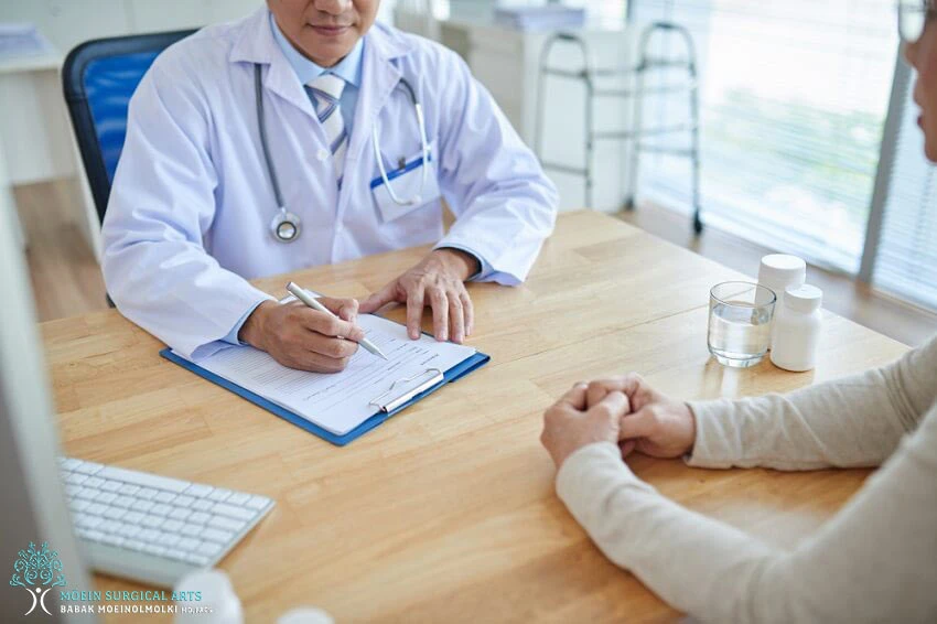 A doctor is talking to a patient at a desk.