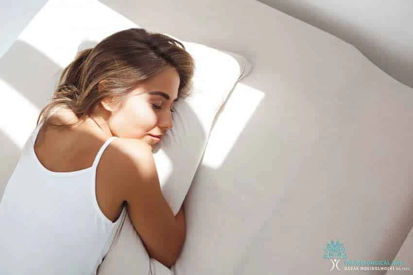 A woman is sleeping on a white bed, peacefully resting and rejuvenating.